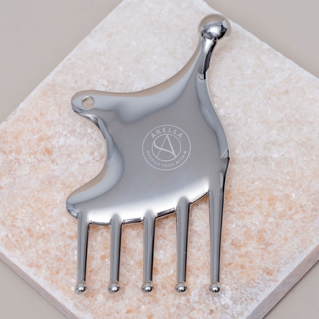 Close-up of the polished Arella face sculpting tool on a stone surface