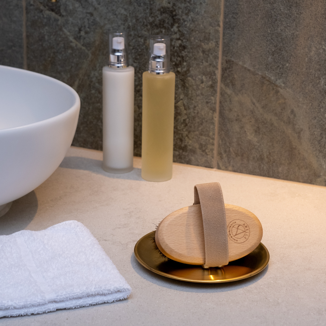 Body brush resting on a copper dish in a luxurious neutral bathroom setting