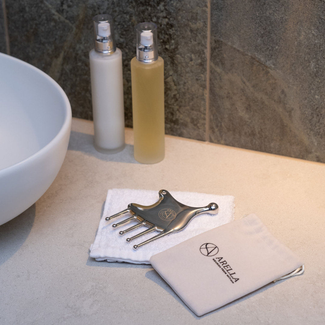Modern bathroom counter with sculpting tool gua sha, hand cream and soap bottles