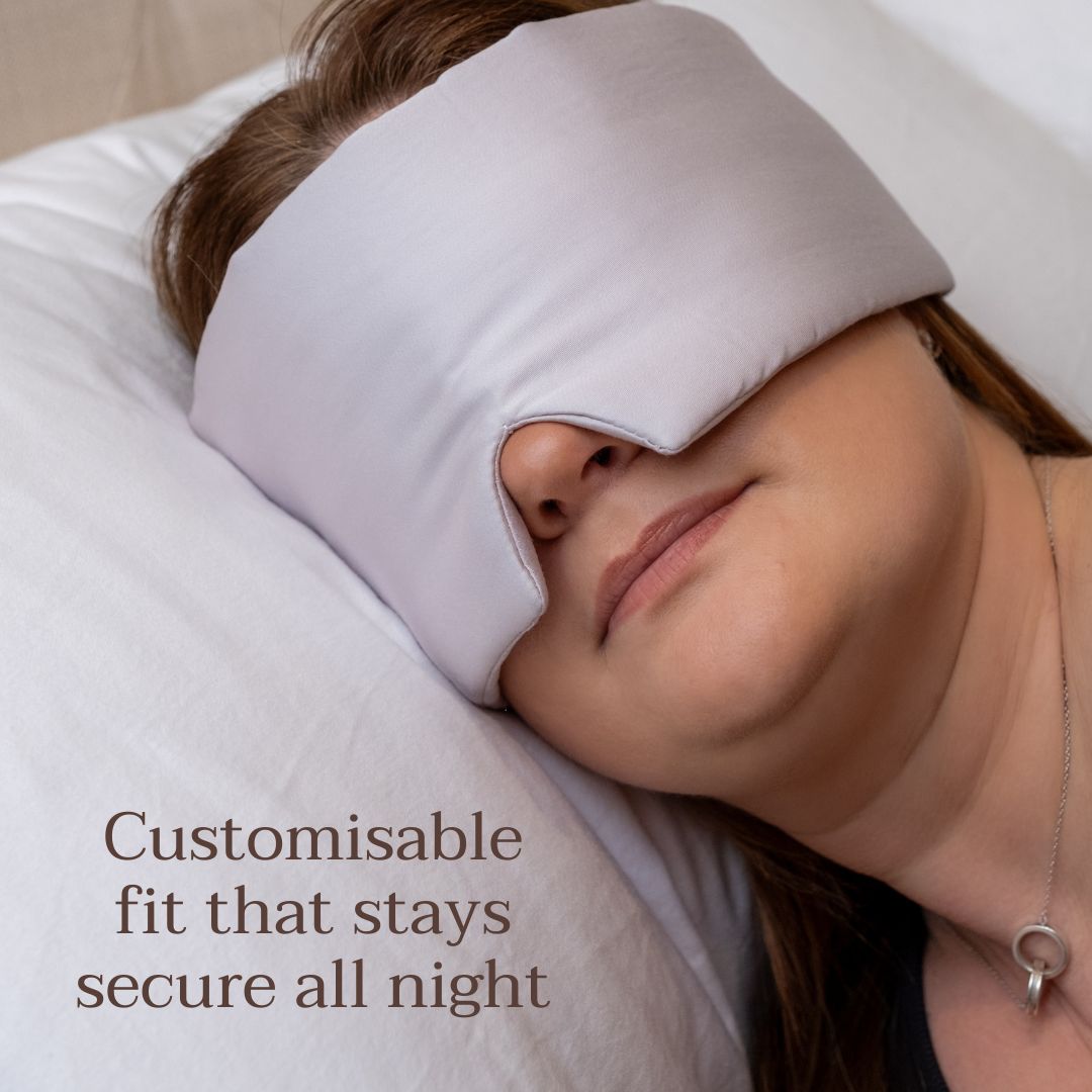 Lady wearing grey eye mask resting on white pillow
