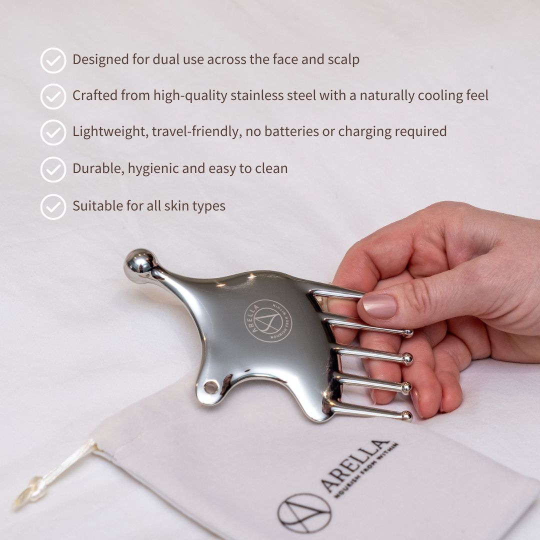 Hand holding the stainless-steel Arella face sculpting tool above its storage pouch